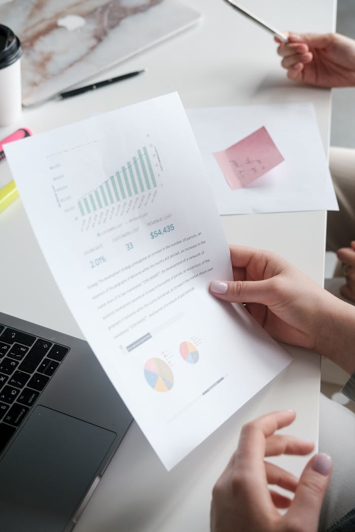 Hands holding a business report with graphs, in a modern office setting.